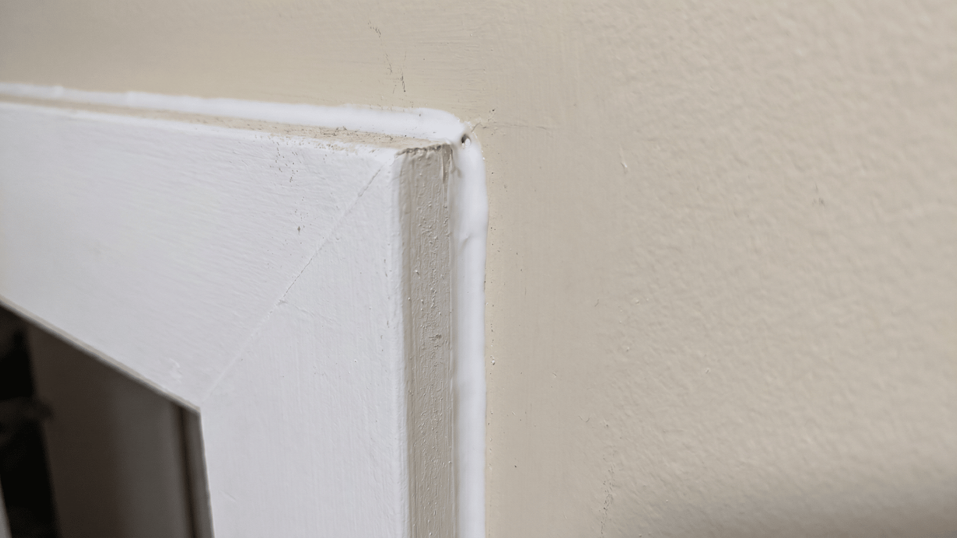 Close view of door frame edge with caulk sealing the gap between the wall and trim