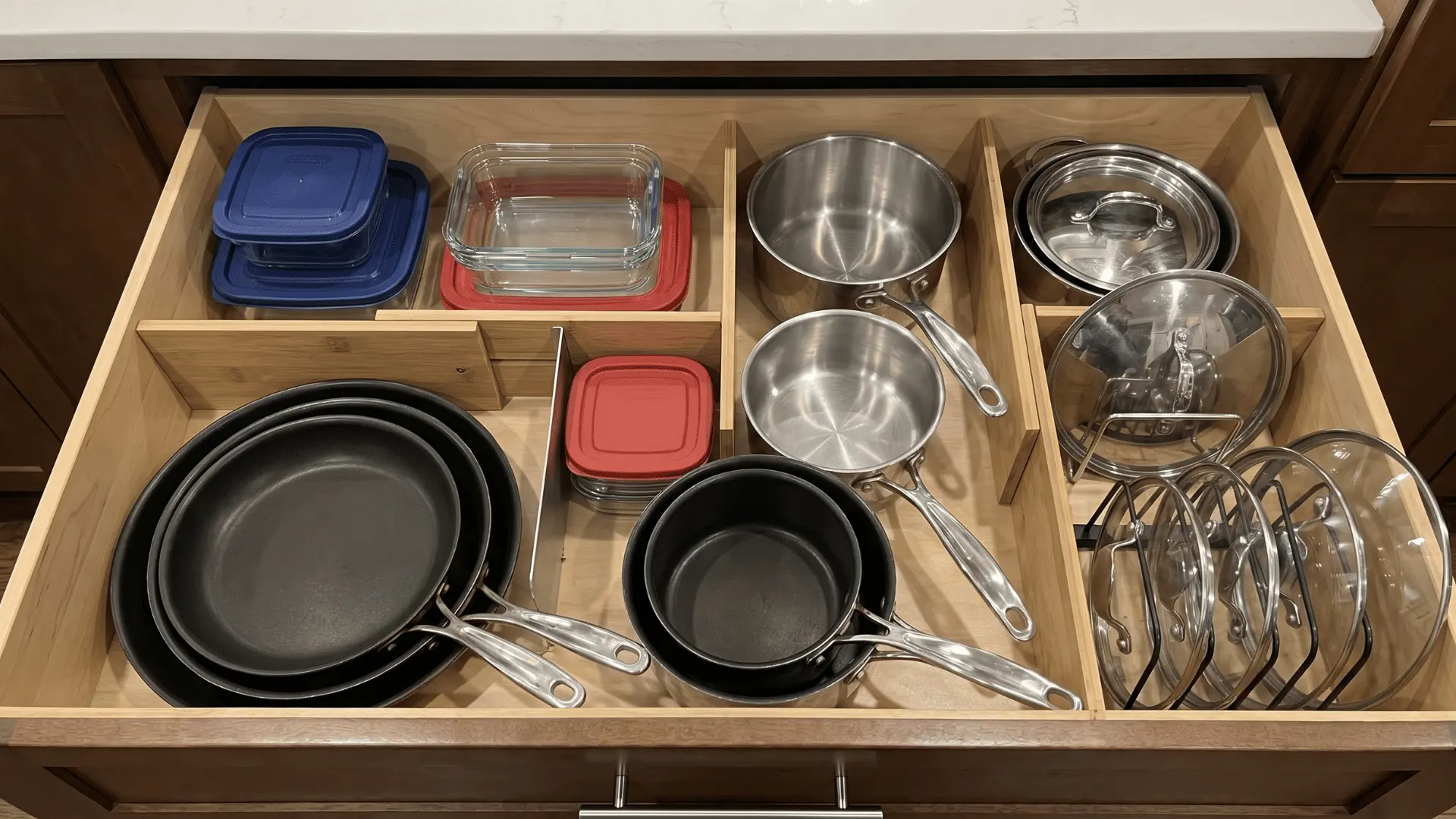 Deep kitchen drawer with pots, pans, lids, and containers organized by size