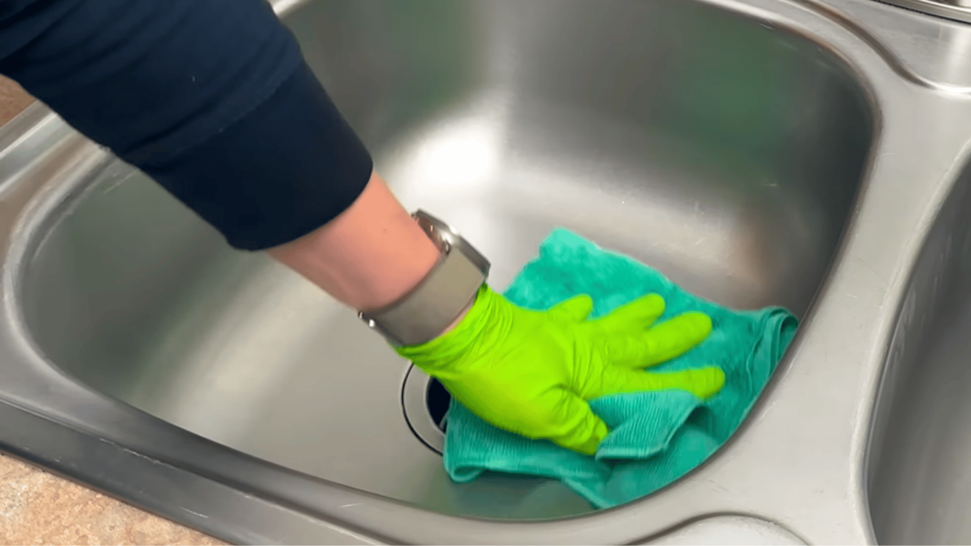 drying a stainless steel sink with a microfiber cloth for a streak free finish