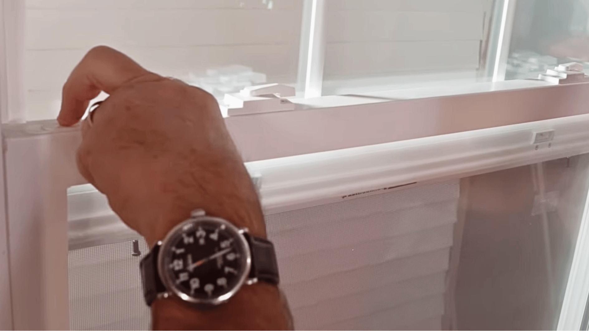 hand lifting a window screen out of the frame for cleaning