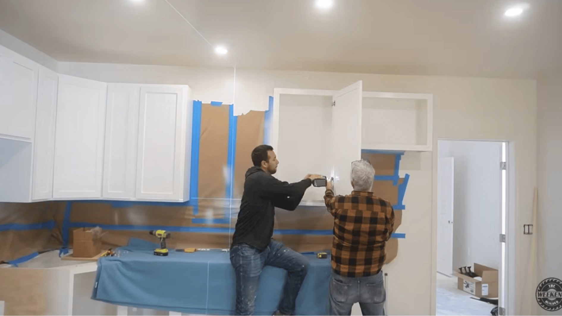 installing upper kitchen cabinets and securing them to the wall during the final stage of a diy kitchen cabinet build.