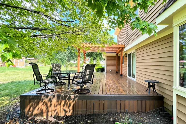 Wooden deck with patio furniture and pergola in a sunny backyard setting