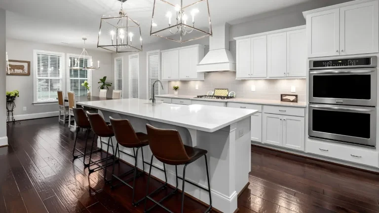 Modern kitchen with large white island, brown chairs, and stainless steel appliances in bright setting