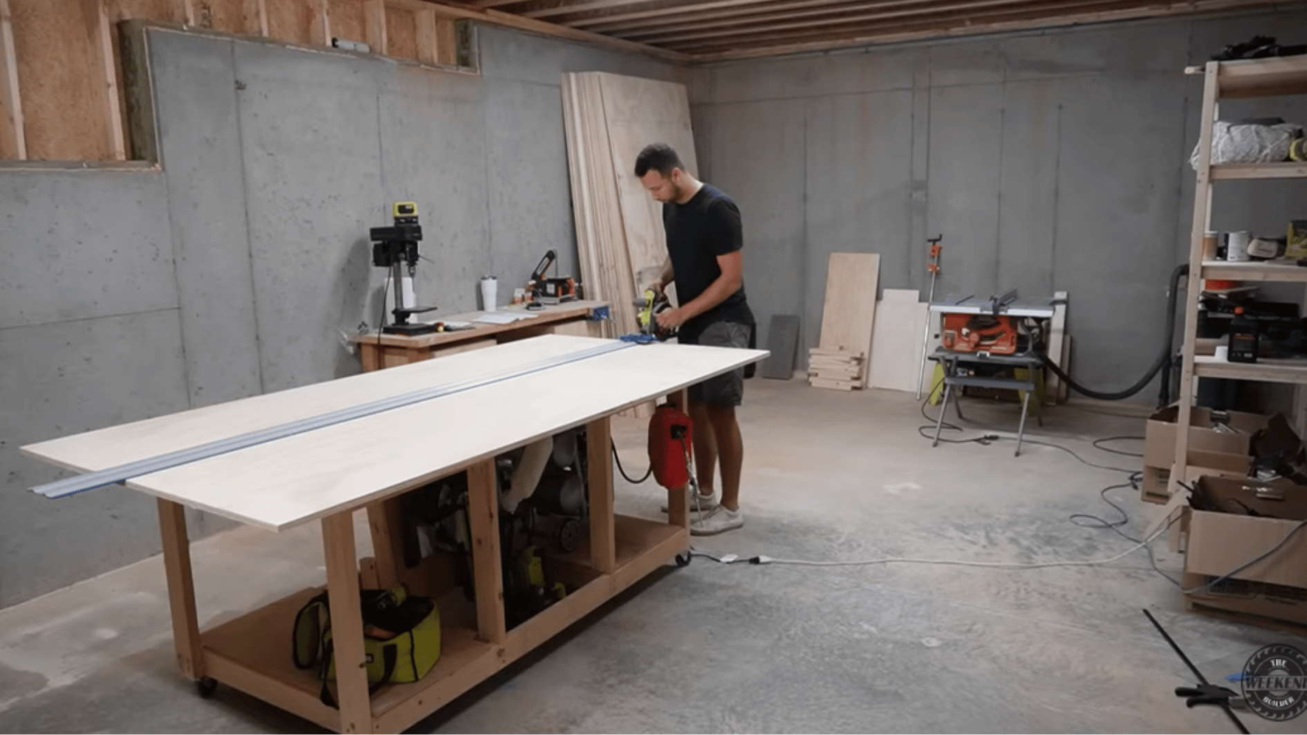 man cutting a plywood sheet with a circular saw and guide rail on a workbench while building diy kitchen cabinets.