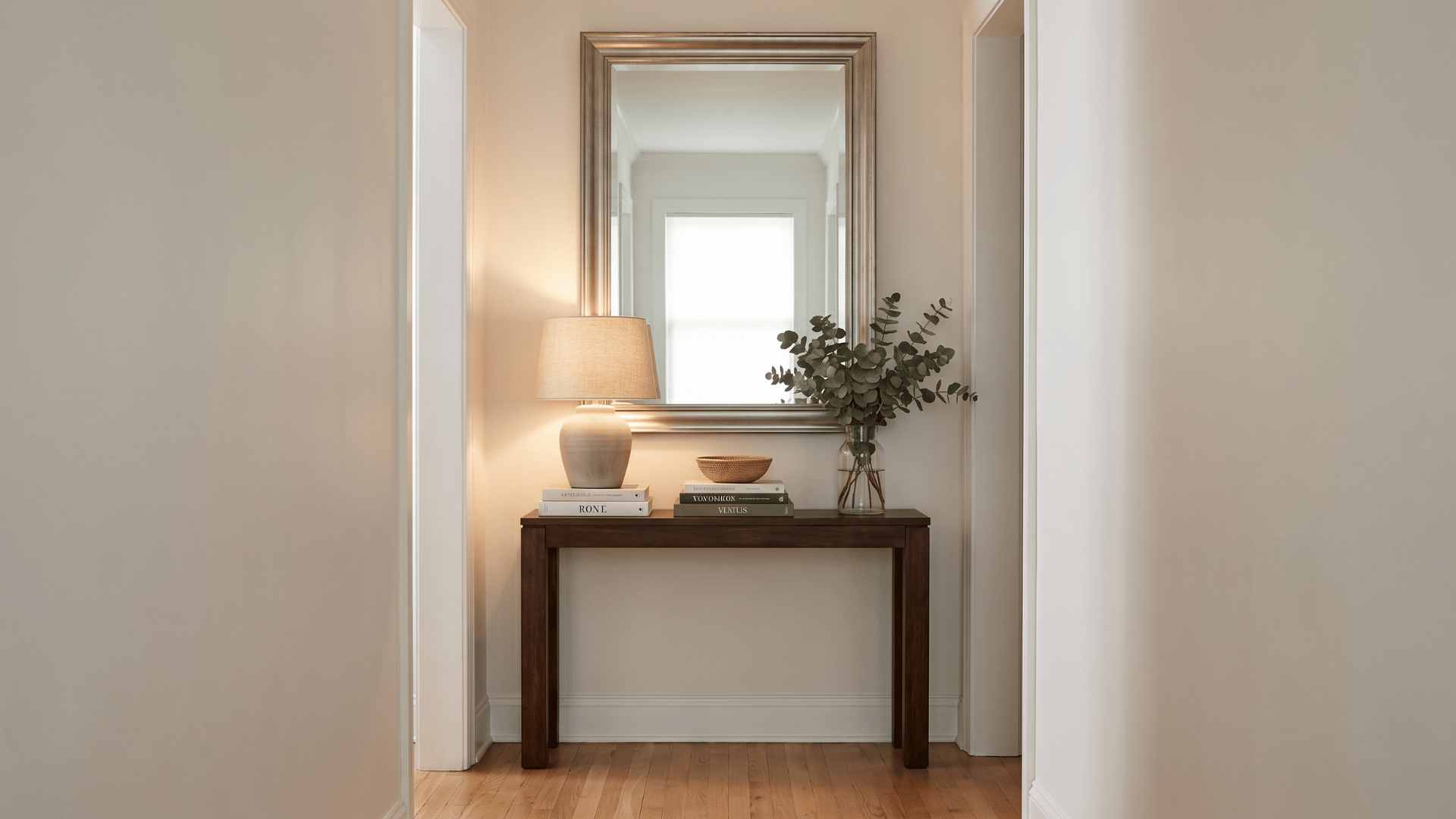 Mirror above a console table with books and a lamp