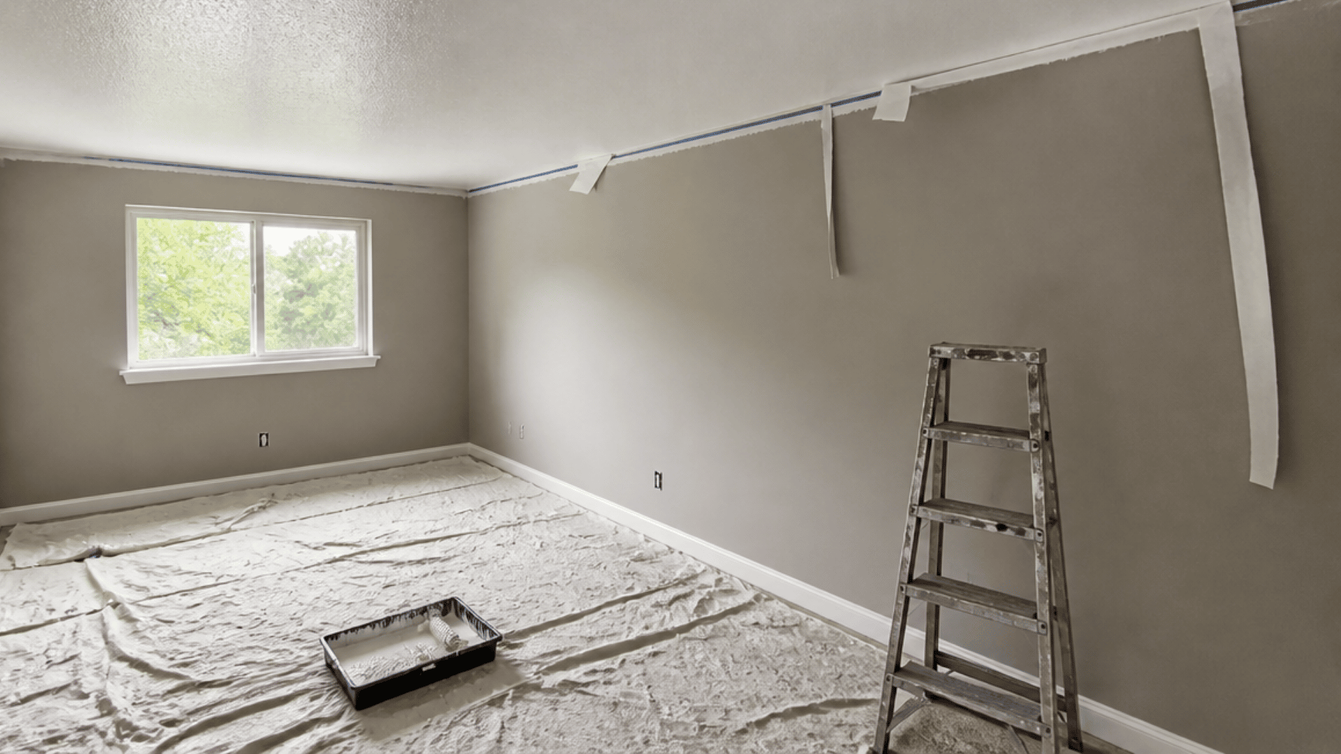 Painted popcorn ceiling with painter’s tape partly removed from the wall edge.