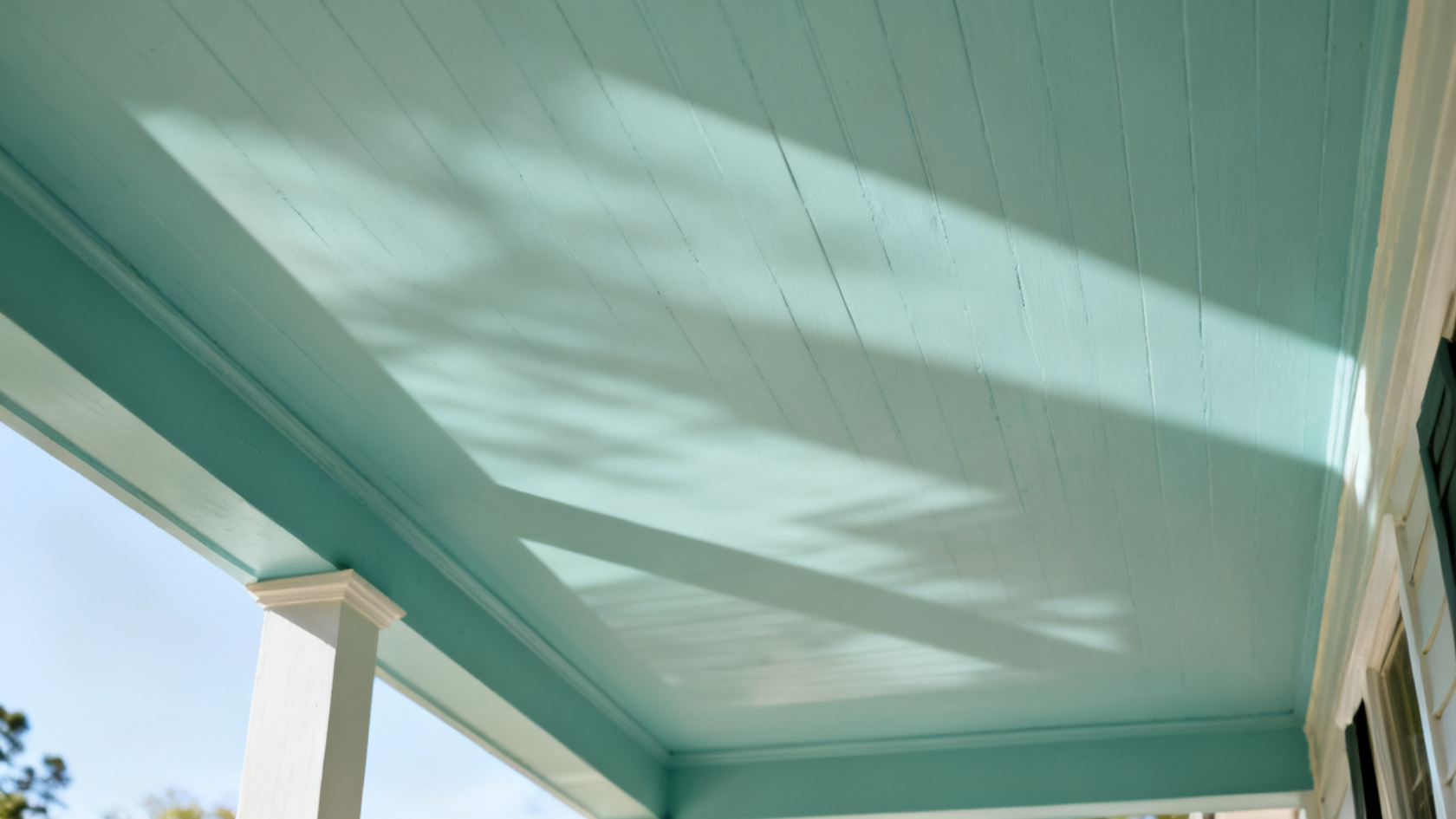 Pale blue-green porch ceiling with natural light and shadow falling across the painted surface.