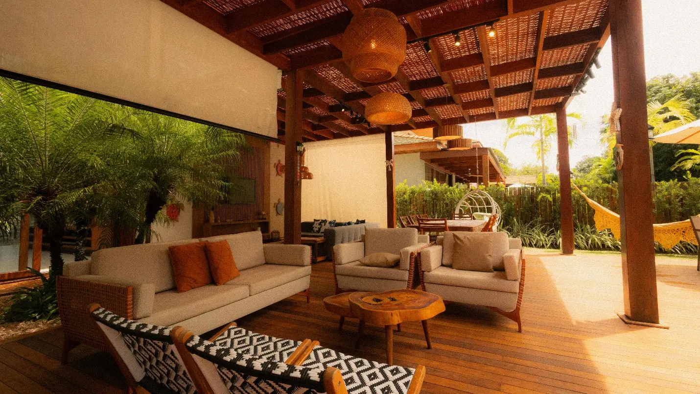 Outdoor lounge area with wicker furniture on wooden deck under pergola with hanging lights
