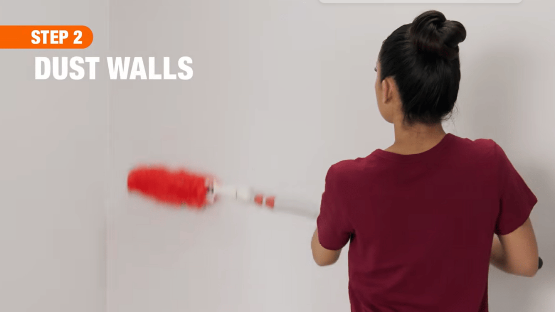 person dusting painted walls with a microfiber duster to remove dirt and cobwebs before washing the surface.