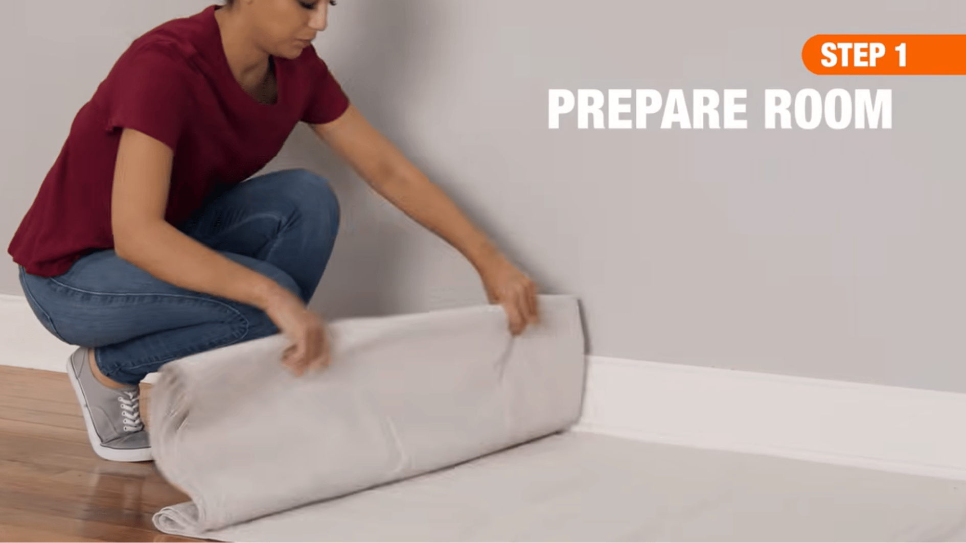 person preparing a room for wall cleaning by laying down a protective sheet before starting the cleaning process.