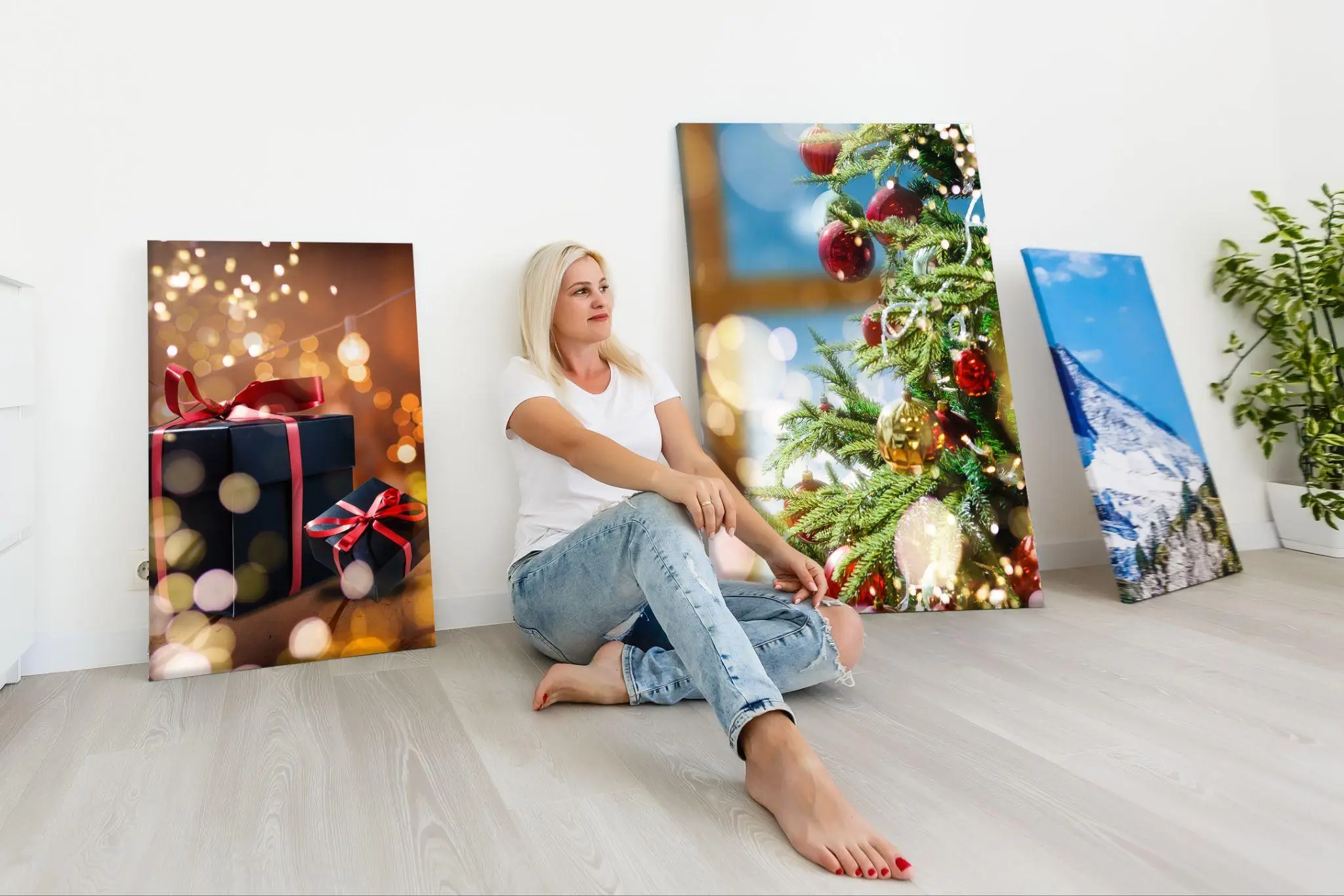 Woman sitting on floor with Christmas-themed photos on white wall