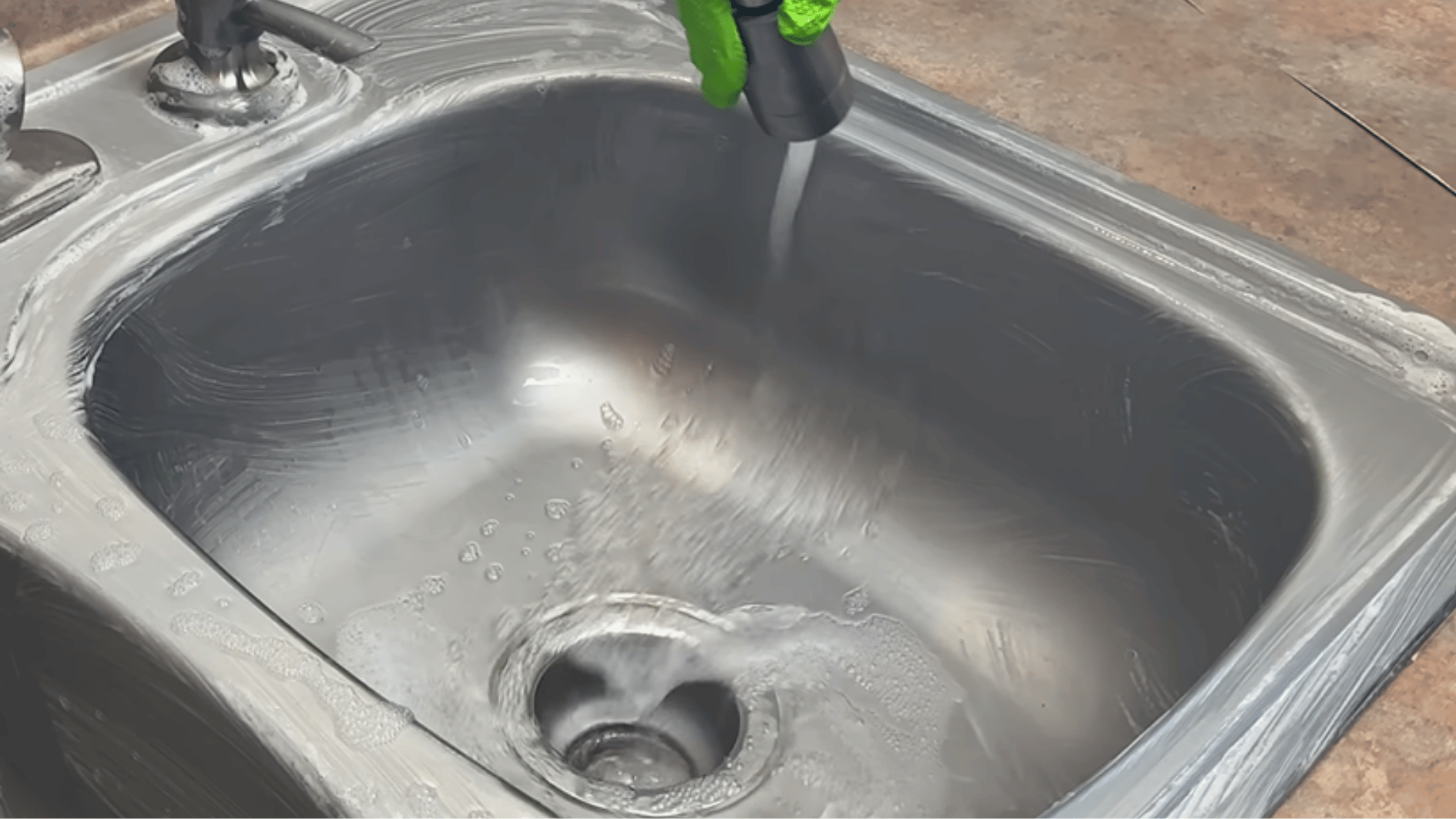 rinsing a stainless steel sink to wash away cleaning residue and buildup