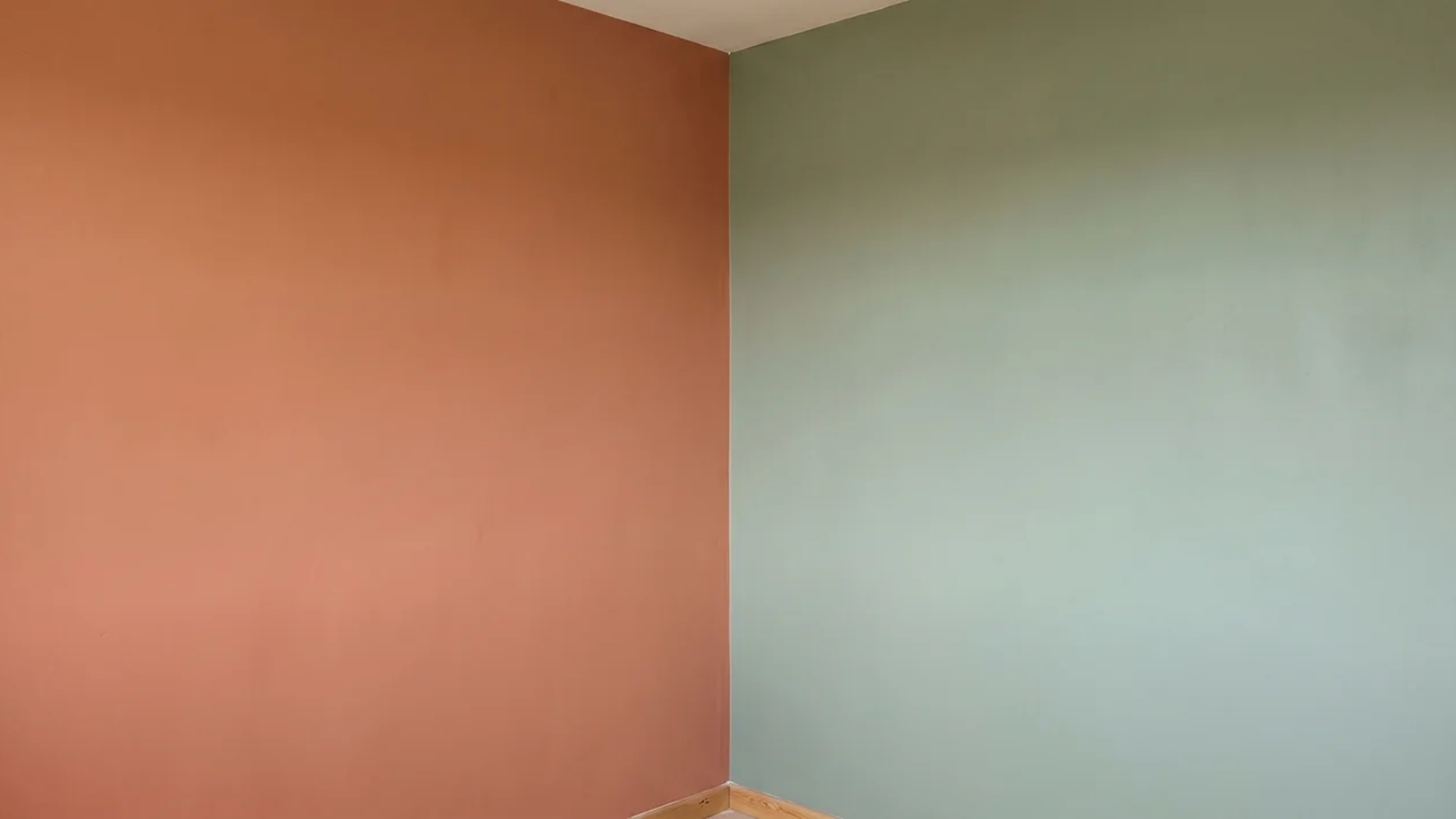 Room corner with a warm terracotta wall meeting a cool sage green wall.