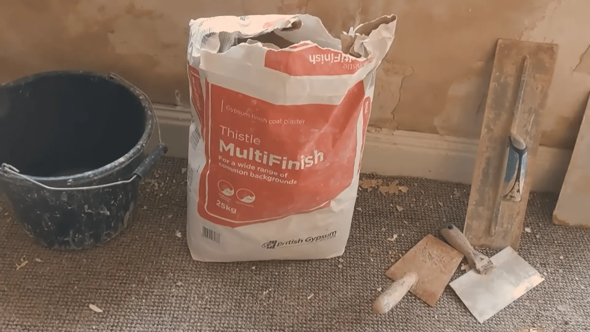 Tools and materials for skim coating multi-finish plaster bag, bucket, and various trowels ready for use