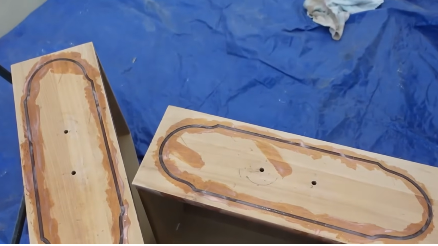 Wooden drawer fronts with applied wood filler or glue around edges placed on a covered work surface
