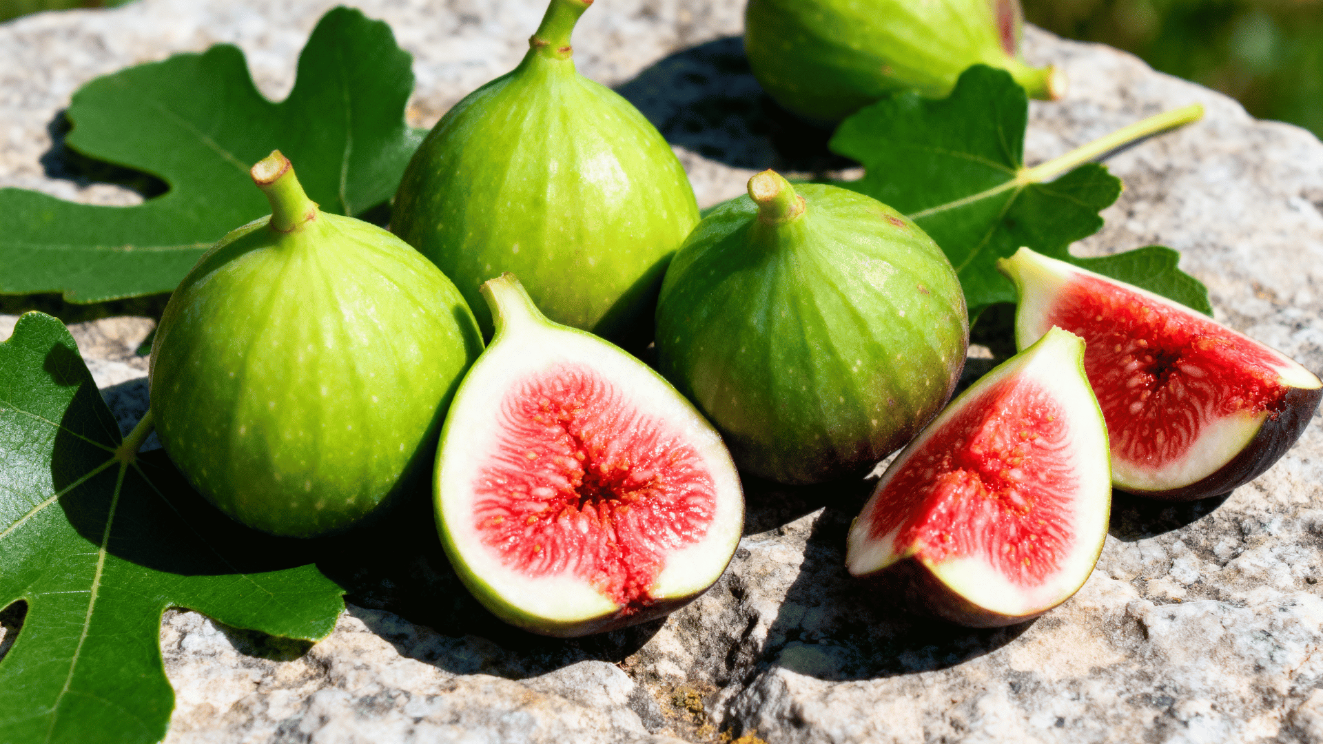 adriatic figs on stone surface green skin sliced revealing bright red pink flesh natural light