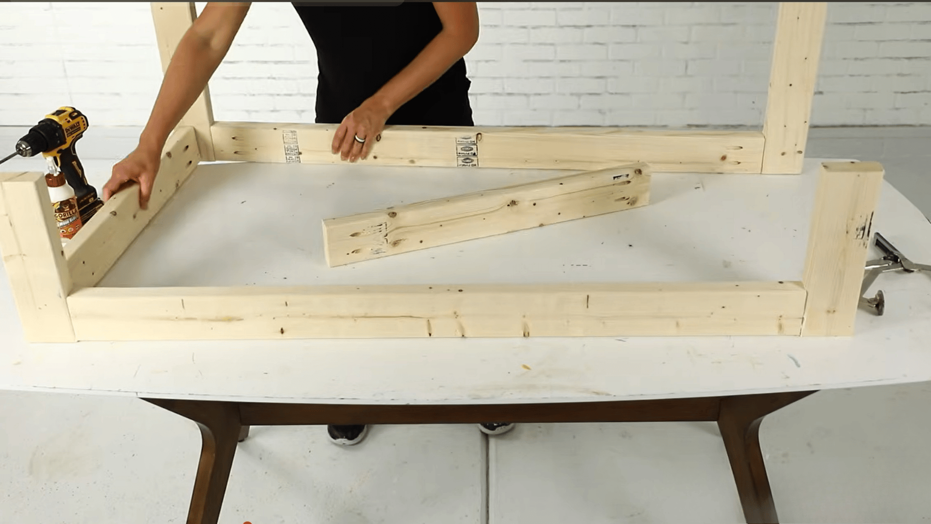 Person assembling a wooden frame structure with boards during a DIY woodworking project.