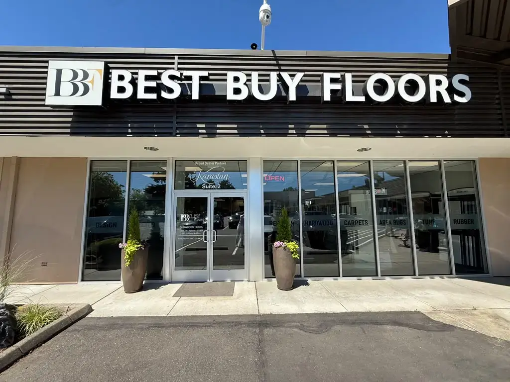 Exterior of a flooring store with large windows and potted plants under clear sky