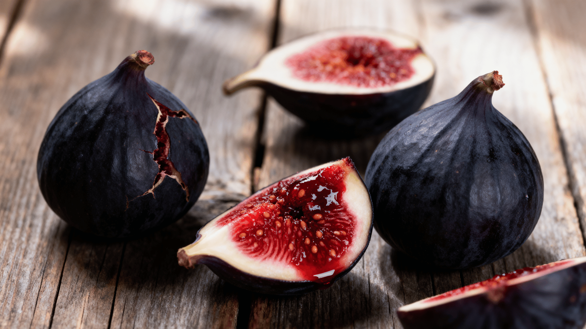 black mission figs on wooden table sliced showing deep red interior natural light rustic setting
