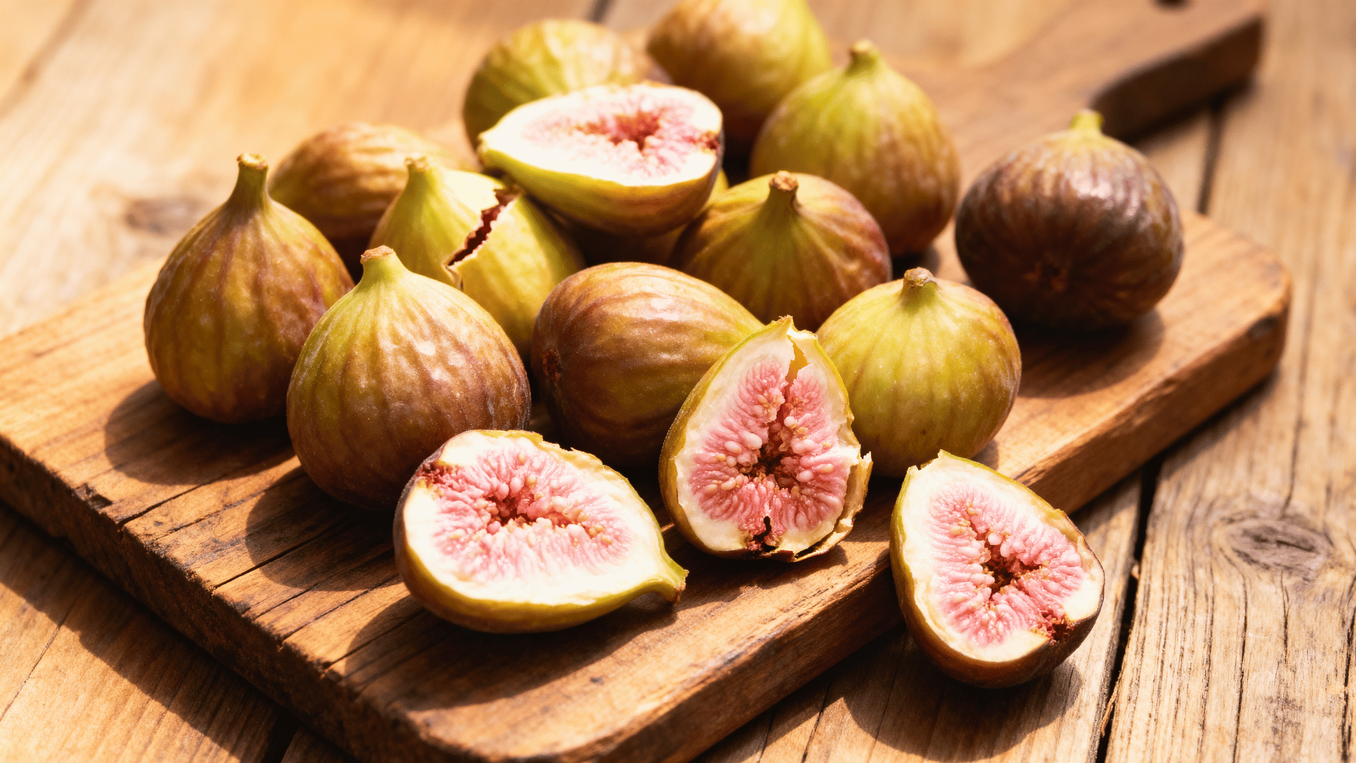 calimyrna figs on wooden board golden green skin sliced showing pink interior warm light