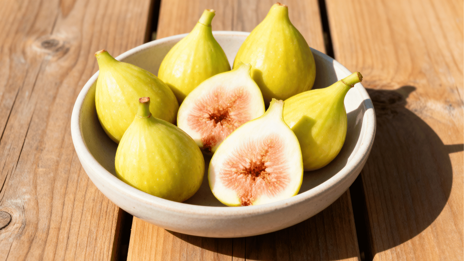 champagne figs pale yellow green in bowl sliced showing soft interior bright natural light