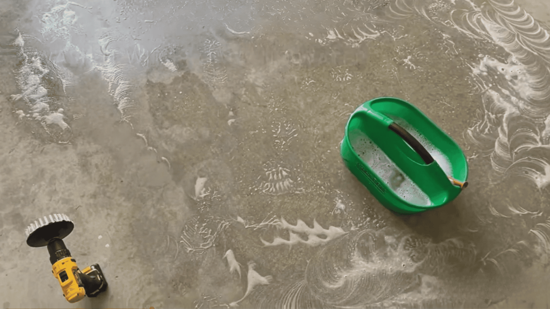 Concrete floor being cleaned with solution and scrubber during paint removal process