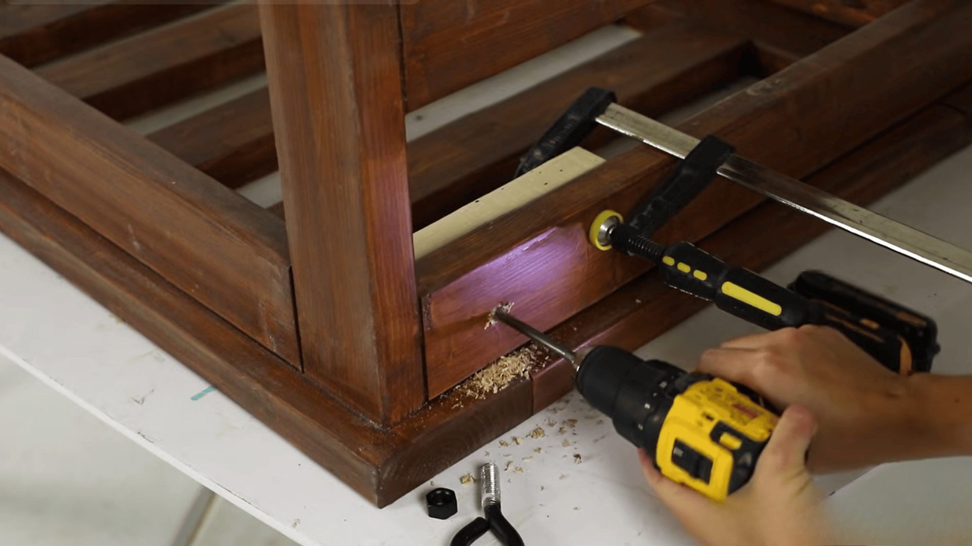 A person using a drill to secure a wooden frame joint during a DIY woodworking project.