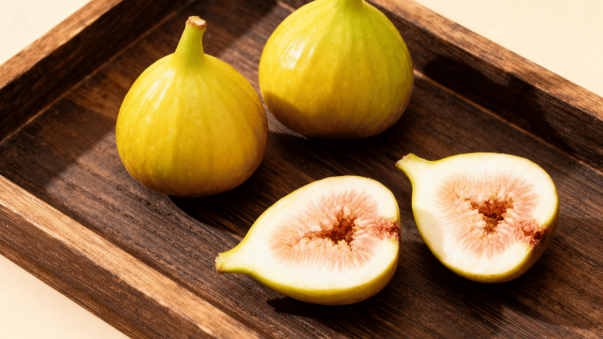 excel figs yellow green skin on tray sliced showing pale firm interior soft lighting