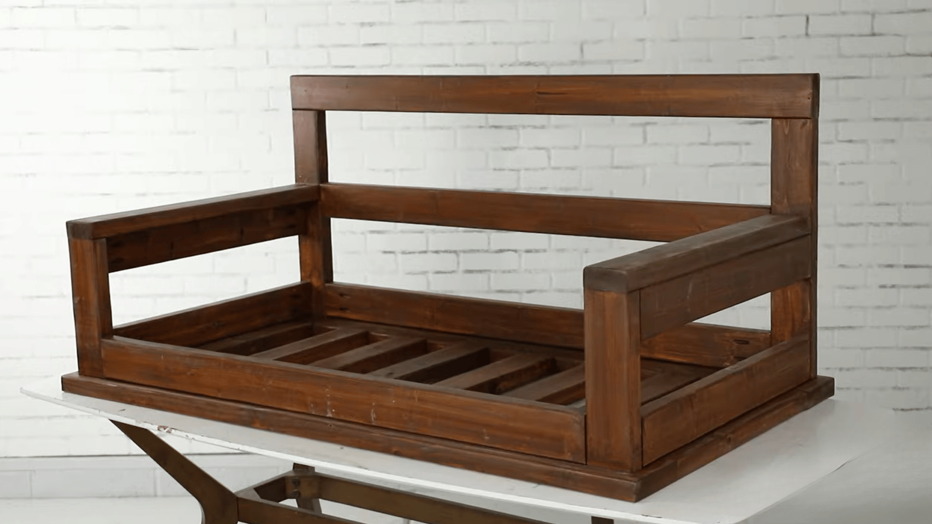 Completed wooden porch swing frame with armrests and back support on a work table.