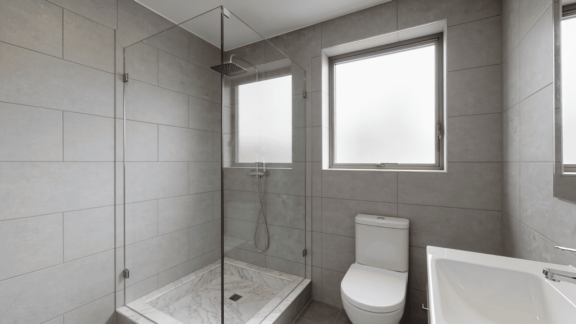 Small bathroom shower with frameless glass panels and open view