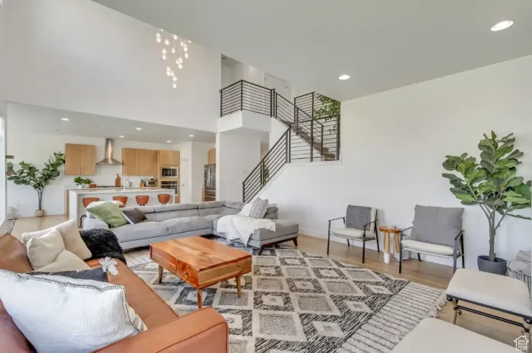 Spacious modern living room with gray sectional sofa, wooden coffee table, and tall green plants