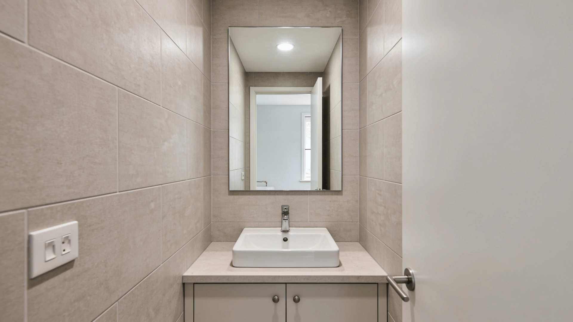 Bathroom sink with a large wall mirror reflecting light and space