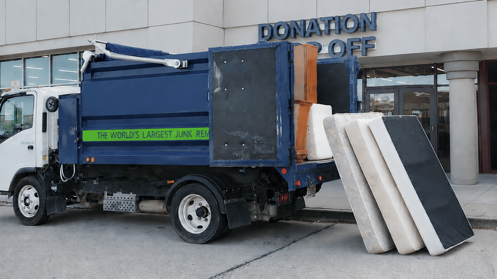 Junk removal truck parked at donation drop-off with mattresses and furniture ready for pickup
