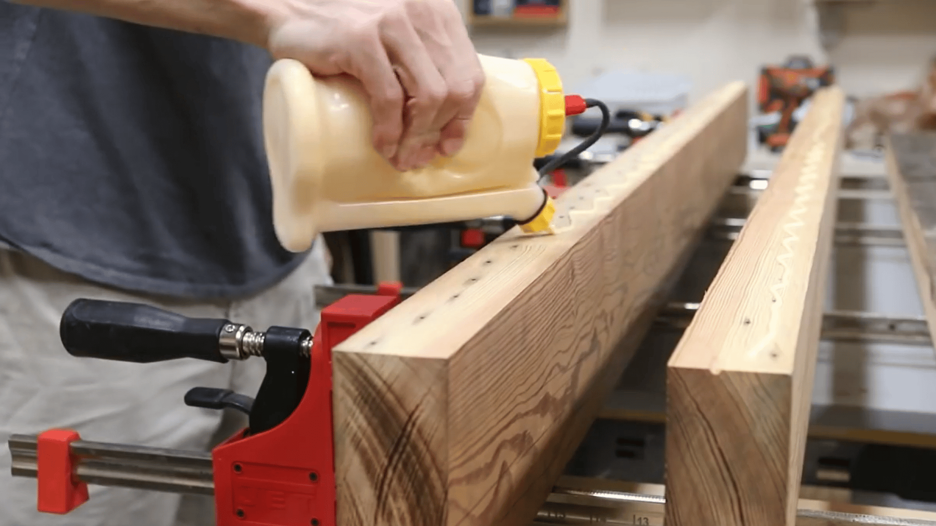 man applying wood glue along large tabletop boards before clamping them together for secure assembly (2)