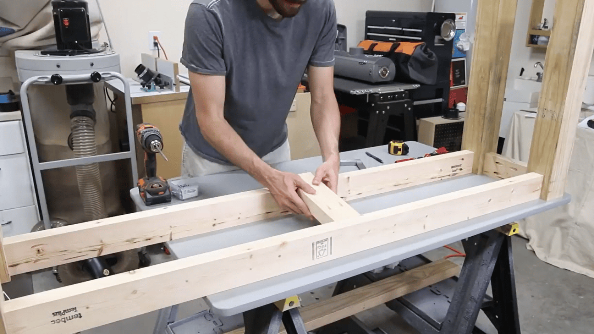 man arranging cut lumber parts to build the rectangular base frame of a wooden console table by hand