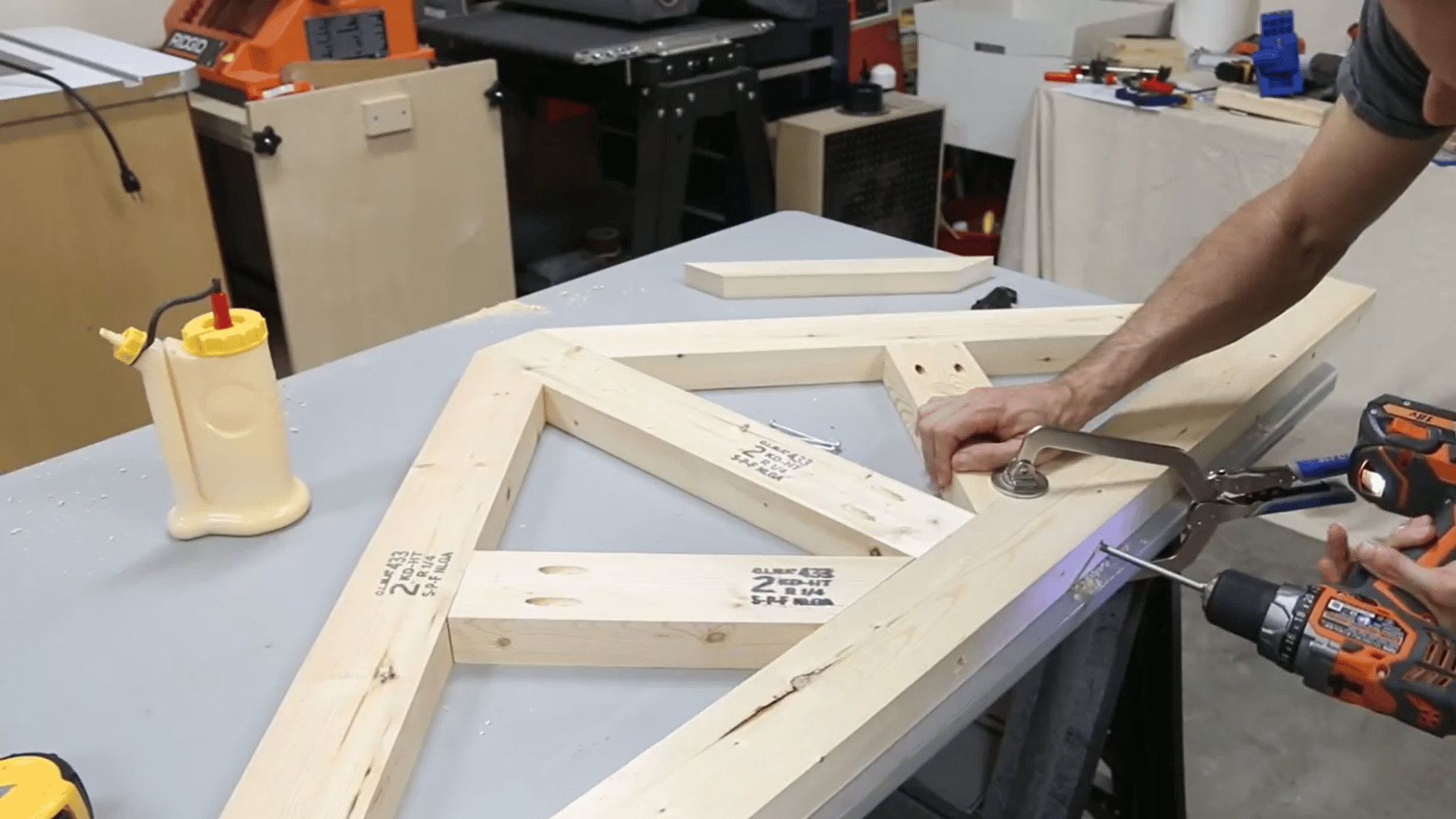 man drilling diagonal wooden braces into the table frame while holding each joint firmly in position