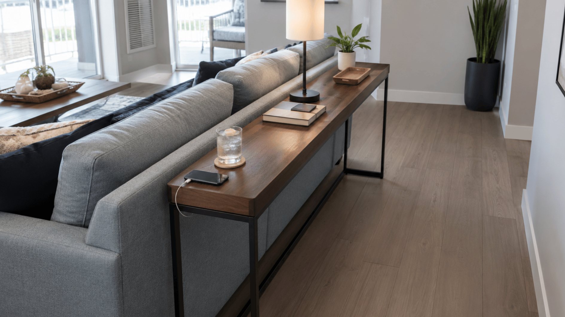 modern sofa table behind couch with lamp books plant and phone charger in living room