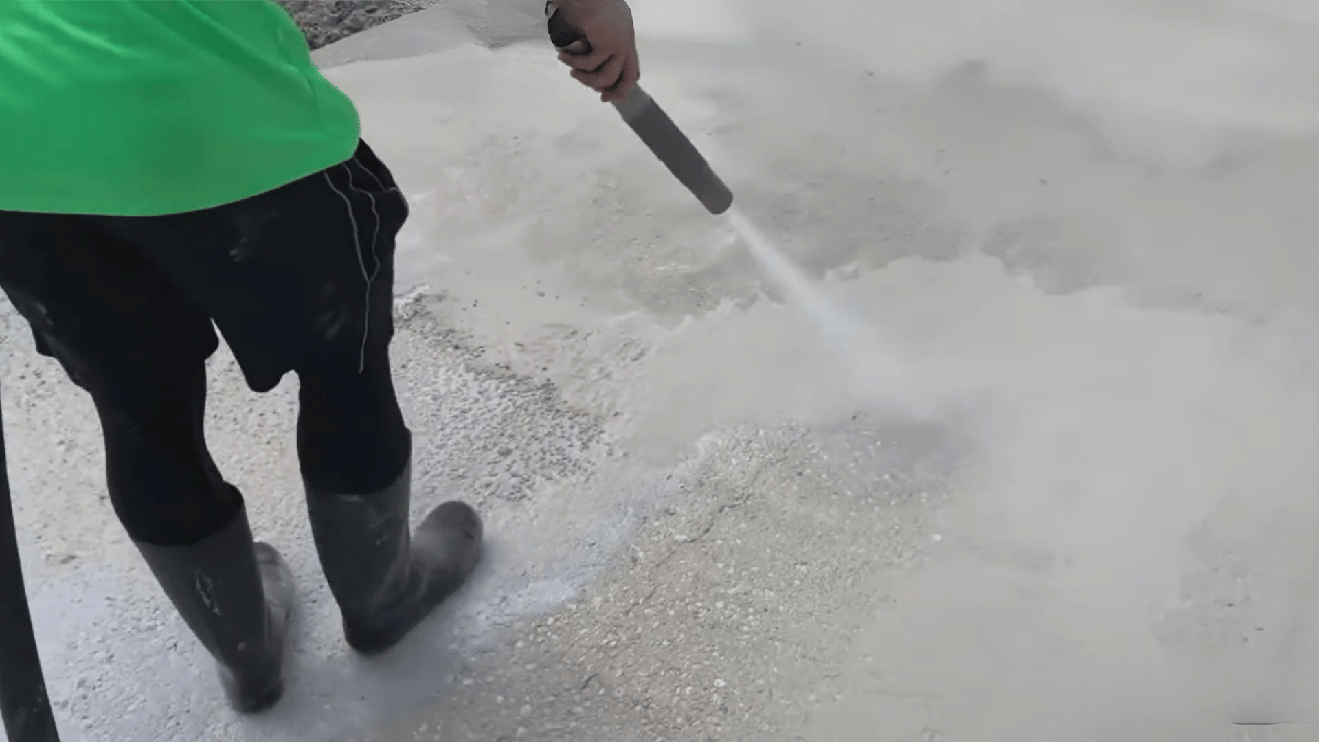 Person pressure washing a concrete surface to remove dirt and paint residue
