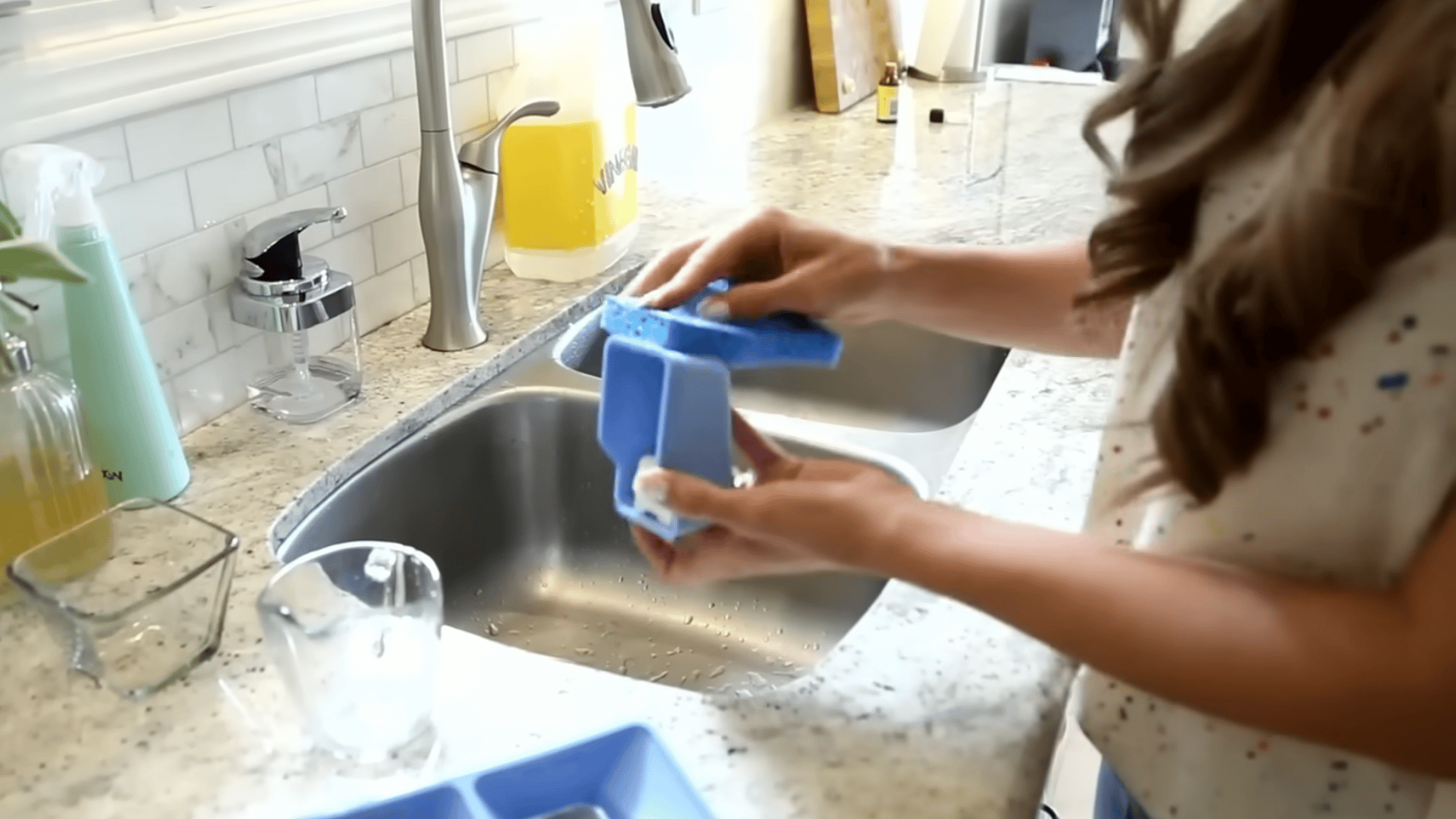 Rinsing and scrubbing the removable detergent drawer over a sink