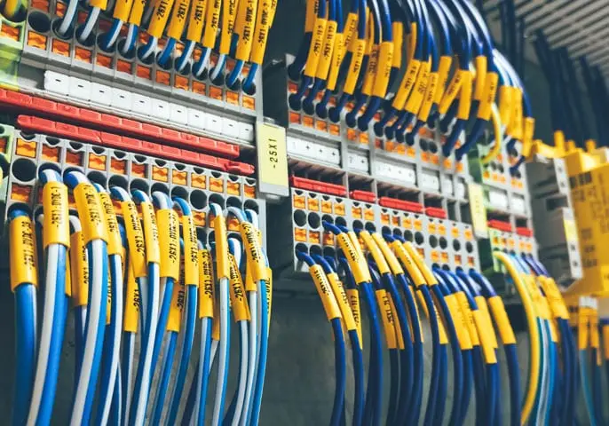 Close-up of electrical panel with labeled wires and circuit breakers in vibrant industrial setting