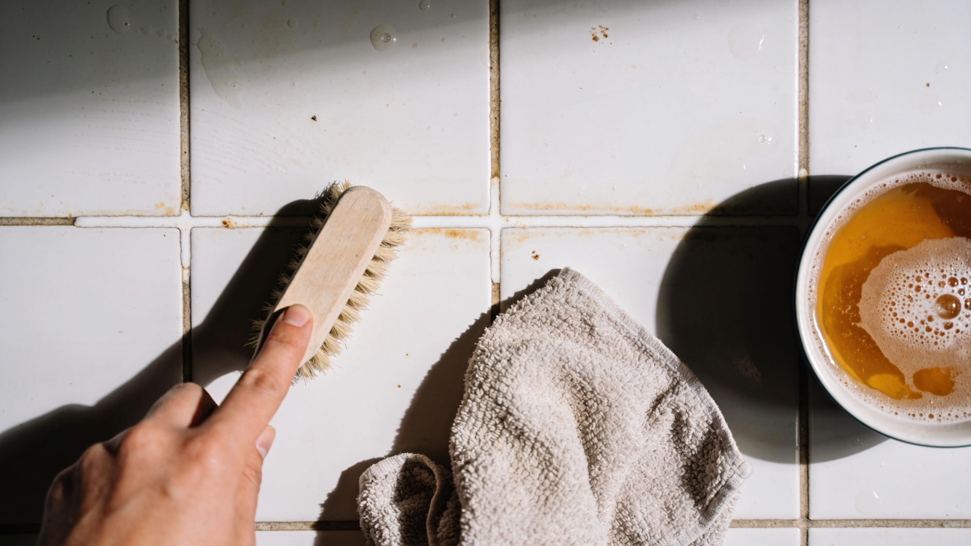 steam cleaner removing dirt from bathroom tile floor beside a towel (1)