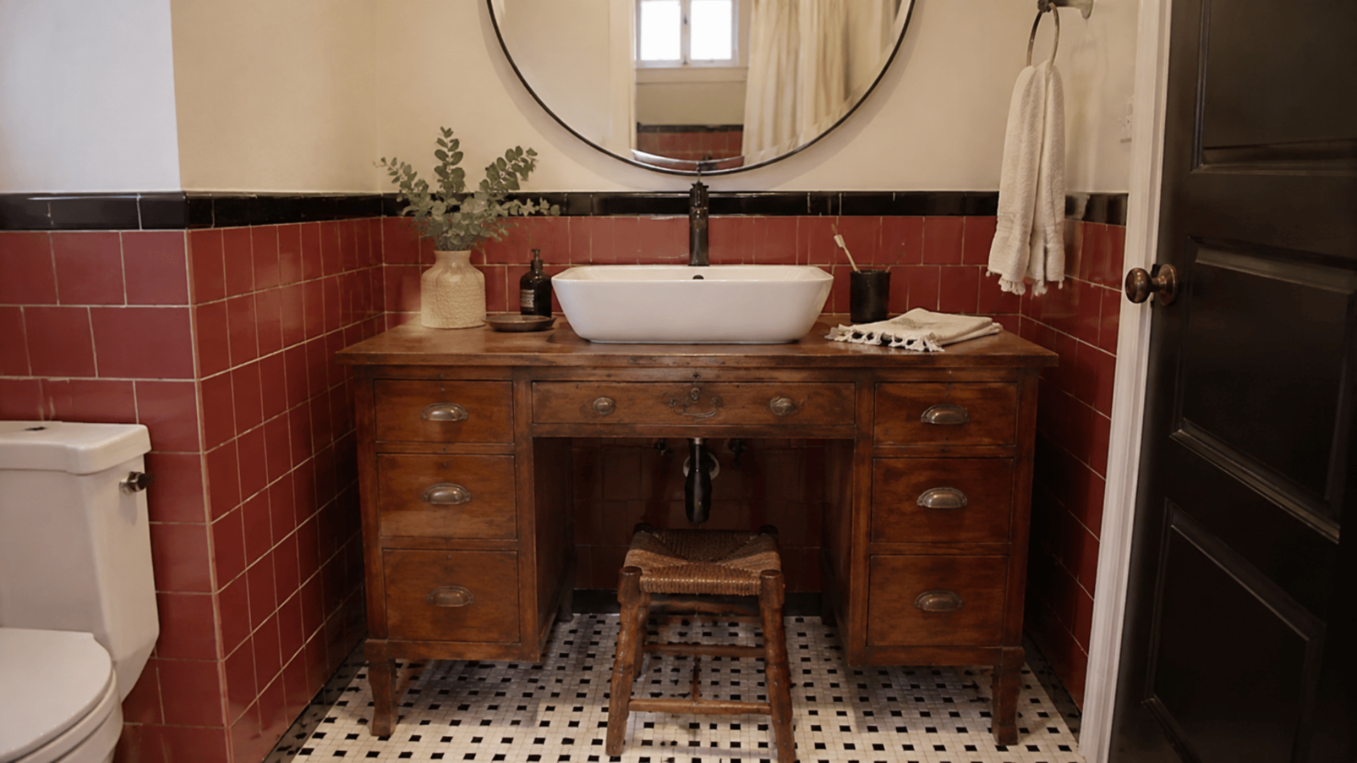 upcycled desk bathroom vanity with a sink cutout in a cozy bathroom setup red tiled wall mirror and bulb lighting