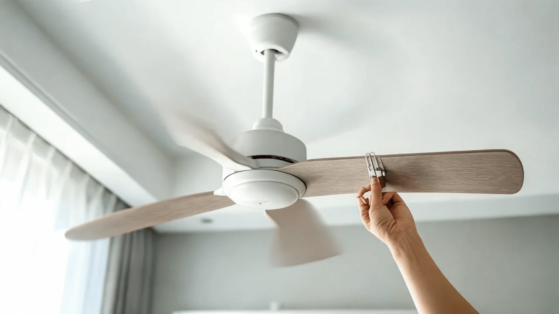 Hand holding balancing clip on ceiling fan blade