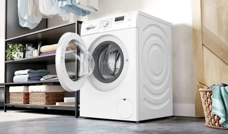 Washing machine with open door in bright laundry room with neatly folded towels and wicker basket