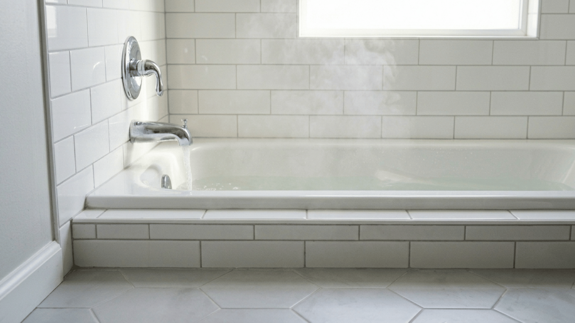 white bathtub filling with water under a bright window, with steam, chrome faucet, white subway tiles and clean floor tiles