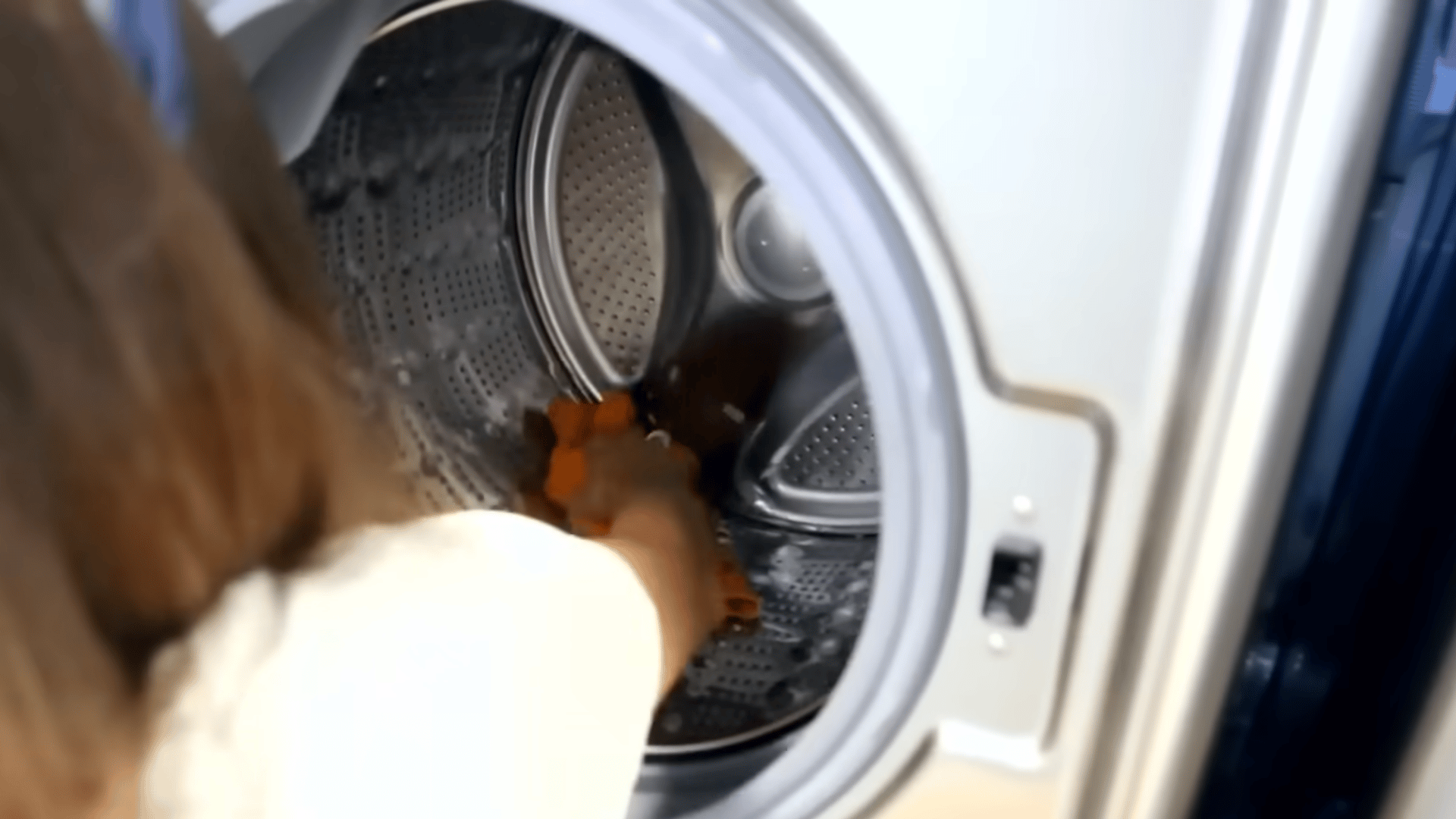 Wiping down the inside of an empty stainless steel washing machine drum