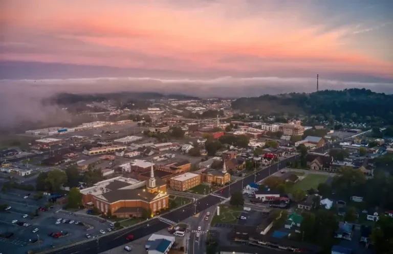 Aerial view of a small town at sunrise with mist and colorful sky
