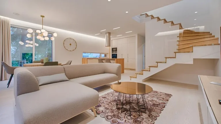 Modern living room with beige sofa, round coffee table, and wooden staircase in open interior design