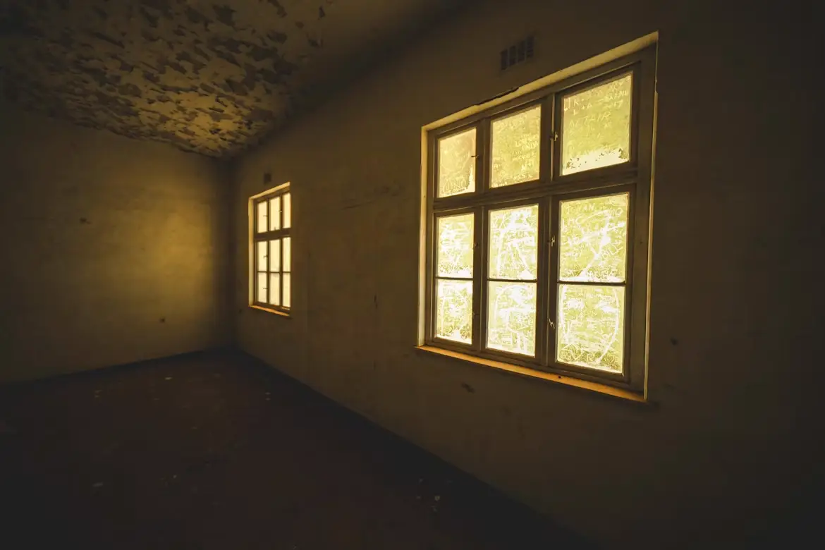 Dimly lit room with textured ceiling and two frosted windows emitting warm light