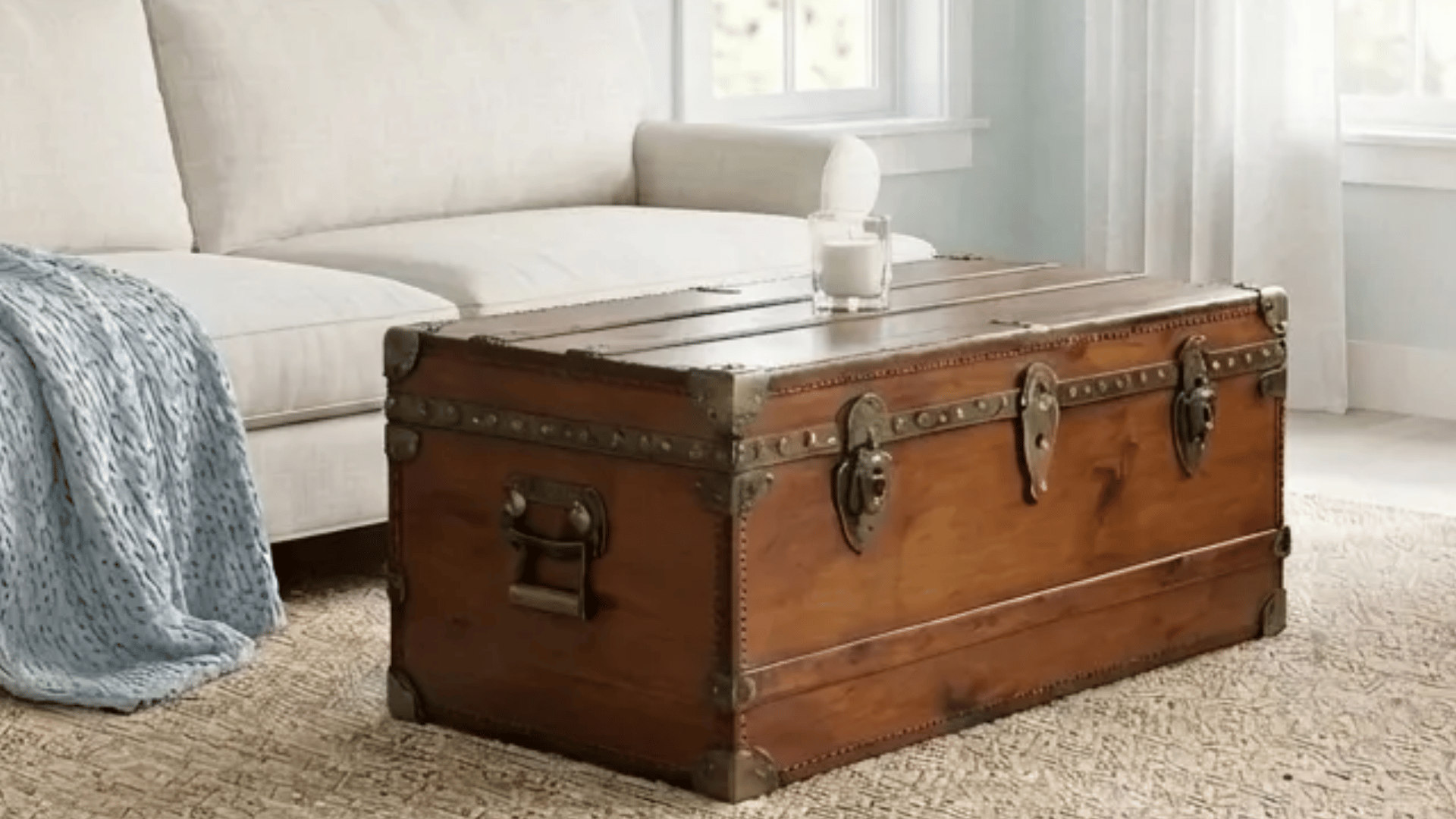 Antique trunk coffee table in a soft neutral living room with natural light.